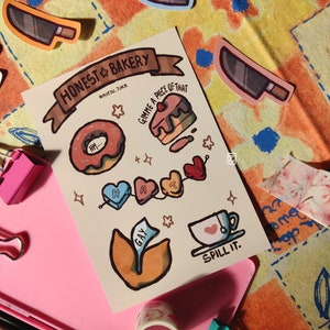 Op de afbeelding: Een set kleurrijke stickers met illustraties met een bakkersthema. De stickers bevatten een donut, een taart, een hartengirlande, een theekopje en een blad met het woord "GAY" erop. De stickers zijn op een witte achtergrond met de tekst "HONEST BAKERY @MITSU.JUKE" bovenaan.