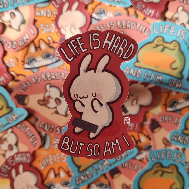 May include: A red and white sticker with a cartoon bunny rabbit and the text "Life is hard but so am I". The sticker is surrounded by other stickers with various designs and text.