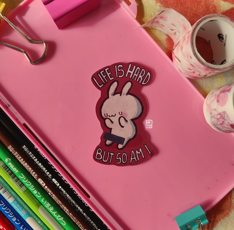 May include: A pink and red sticker with a cartoon bunny and the text "Life is hard but so am I".
