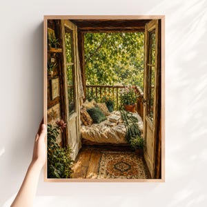 Puede incluir: Una lámina de arte mural enmarcada que representa una puerta abierta hacia un balcón soleado. La escena muestra una cama acogedora con cojines estampados, una manta verde y plantas en macetas. Una alfombra estampada cubre el suelo de madera.