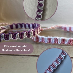 May include: Two friendship bracelets with a wavy pattern. The first bracelet is white and purple, and the second bracelet is white and pink. The bracelets are on a wooden surface. Fits small wrists! Customize the colors!