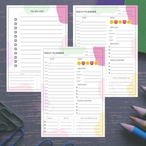 Op de afbeelding: Een printbare dagelijkse planner met secties voor takenlijsten, stemmingstracking, maaltijdplanning, hoofddoelen, evenementen en vergaderingen, en dankbaarheid. De planner heeft een lichtgroen, roze en geel kleurenschema met abstracte vormen.