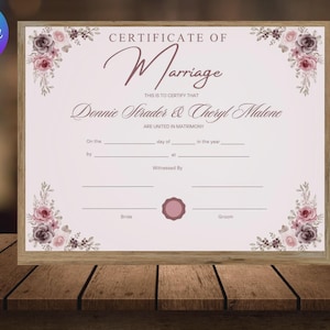 Op de afbeelding: Een rechthoekig huwelijkscertificaat met de tekst Certificate of Marriage, Donnie Strader & Cheryl Malone en lege regels voor datum, locatie en handtekeningen, versierd met donkerroze en grijze bloemillustraties in de hoeken.