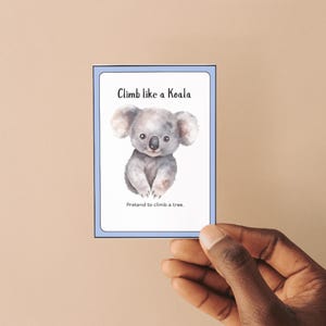K&ouml;nnte beinhalten: Eine blaue und wei&szlig;e Karte mit einem Karikatur-Koala-B&auml;ren und dem Text "Klettere wie ein Koala. Tu so, als w&uuml;rdest du auf einen Baum klettern."