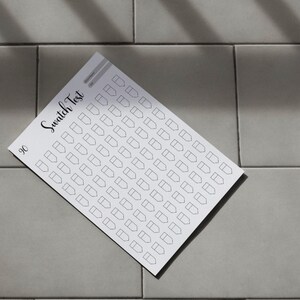 May include: A white swatch test sheet with a grid of small, outlined shapes, labeled "Swatch Test" in cursive script. The number "90" is in the lower left corner. The sheet is on a gray tiled surface.
