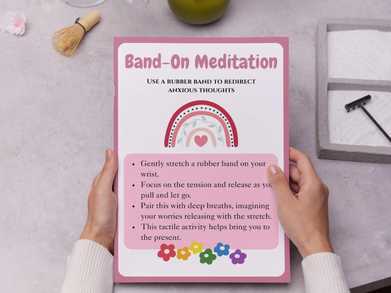 May include: Pink and white printable poster with a rainbow and heart design. The poster has the text "Band-On Meditation" and instructions on how to use a rubber band to redirect anxious thoughts.
