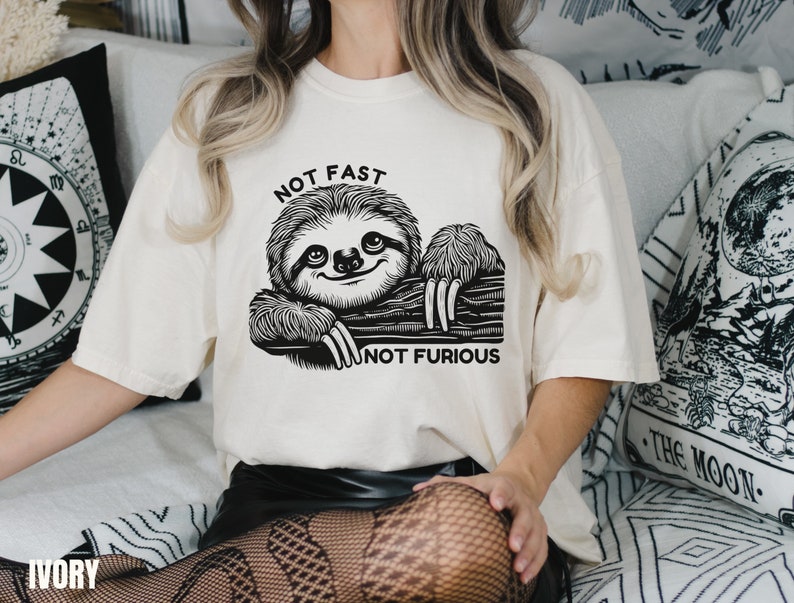 May include: A white t-shirt with a black and white illustration of a sloth and the text "Not Fast Not Furious".