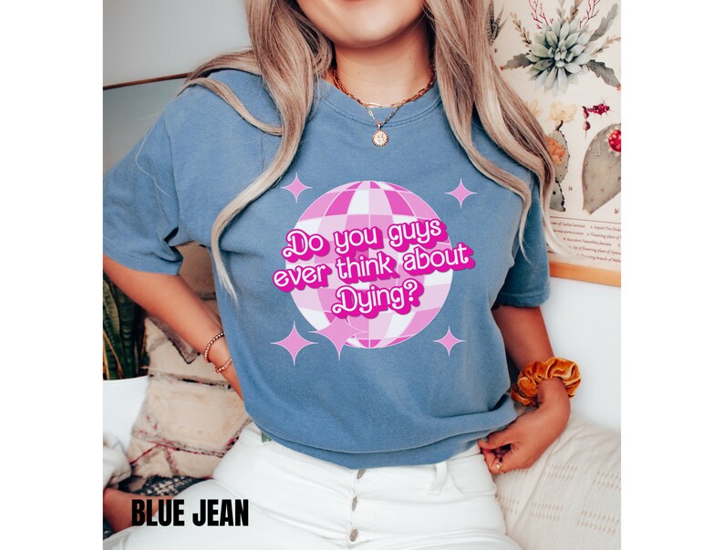 May include: A blue t-shirt with a pink disco ball graphic and the text "Do you guys ever think about Dying?" in pink.