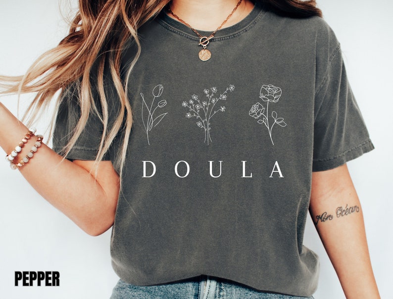 May include: A gray t-shirt with a white graphic of three flowers and the word "DOULA".
