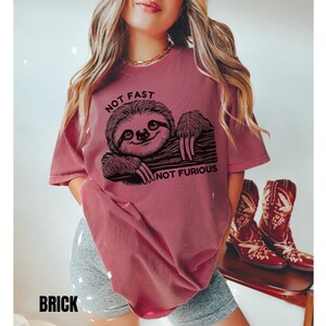 May include: A maroon t-shirt with a black graphic of a sloth and the text "Not Fast Not Furious".