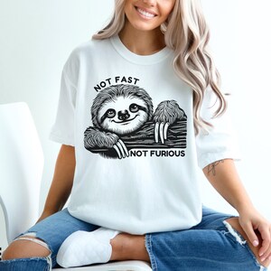 May include: White t-shirt with a black and white illustration of a sloth with the text "Not Fast Not Furious".