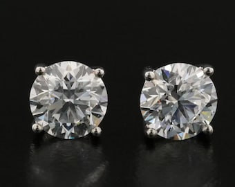 May include: A pair of round diamond stud earrings set in silver.