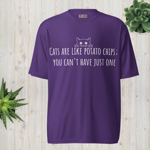 Puede incluir: Camiseta morada con un gato blanco asomándose por la parte superior y el texto "Los gatos son como las patatas fritas; no puedes tener solo una."