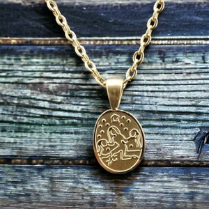 May include: Gold chain necklace with a gold oval pendant featuring a zodiac symbol. The pendant has a detailed design of two figures with a star above them.