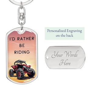 May include: A silver keychain with a red and black off-road vehicle on a sunset background. The keychain says "I'd Rather Be Riding". The back of the keychain is blank and can be personalized with an engraving.