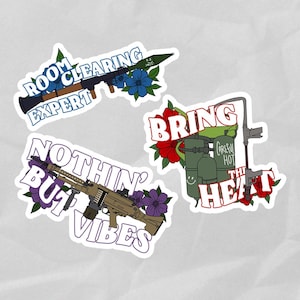 May include: Three colorful stickers with military-themed designs. The first sticker says "Room Clearing Expert" with a blue background and a cartoon grenade launcher. The second sticker says "Bring The Heat" with a red background and a cartoon flamethrower. The third sticker says "Nothin' But Vibes" with a purple background and a cartoon machine gun.