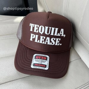 May include: Brown trucker hat with a white mesh back and the text "TEQUILA, PLEASE." in white letters. The hat has a black label with the text "OTTO WORLD FAMOUS FOAM FRONT OSFM TRUCKER DURABLE SNAP CLOSURE" in white letters.