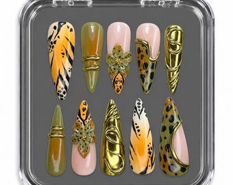 May include: A set of ten stiletto-shaped press-on nails in a clear plastic case. The designs feature a mix of olive green, orange, and nude tones with black animal print patterns, raised gold metallic accents, and three-dimensional floral details.