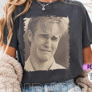 May include: Dark gray t-shirt featuring a sepia-toned image of a man crying. The shirt has the word "SUMBERHIT" printed at the bottom and the words "PEPPER" and "COMFORT COLORS" on the right side.