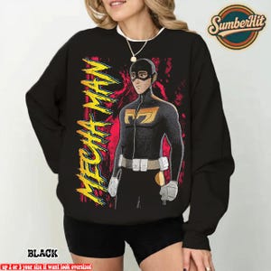 May include: Black sweatshirt with a superhero graphic and the text "MECHA MAN" in yellow. The superhero is in a black and gold suit. The sweatshirt also has the word "BLACK" at the bottom, with a logo in the top right.