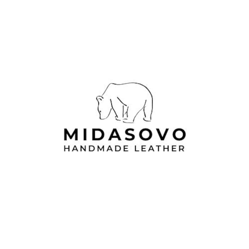 Puede incluir: Logotipo minimalista con un contorno de oso sobre el texto "MIDASOVO HANDMADE LEATHER". El oso se representa con una l&iacute;nea continua simple, y el texto est&aacute; centrado debajo sobre un fondo blanco. La fuente es limpia y sans-serif.