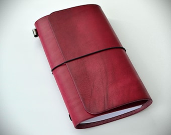 Refillable trifold leather traveler’s journal features burnished edges, secure elastic closure, and a timeless design