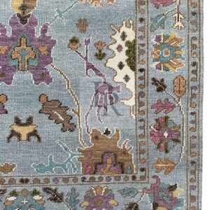 K&ouml;nnte beinhalten: Ein blauer Teppich mit einem floralen Muster in Braun-, Lila- und T&uuml;rkist&ouml;nen. Der Teppich hat einen Fransenrand.