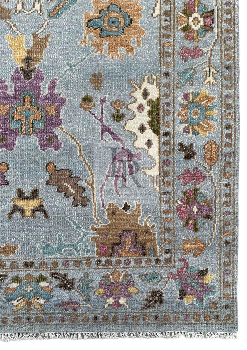 K&ouml;nnte beinhalten: Ein blauer Teppich mit einem floralen Muster in Braun-, Lila- und T&uuml;rkist&ouml;nen. Der Teppich hat einen Fransenrand.