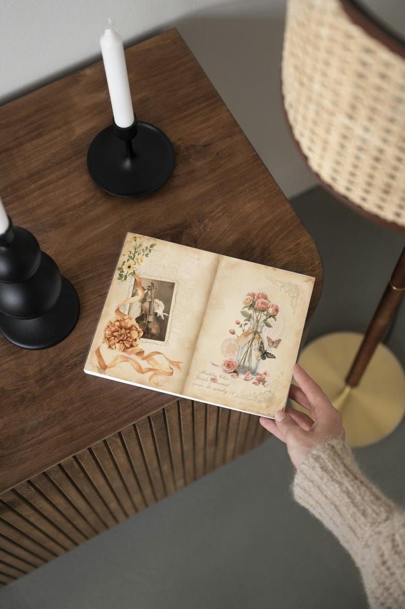 K&ouml;nnte beinhalten: Ein offenes Journal mit Illustrationen im Vintage-Stil von Blumen, Schmetterlingen und einer Geige. Das Journal wird von einer Person gehalten und liegt auf einer dunklen Holzoberfl&auml;che. Ein schwarzer Kerzenhalter mit einer wei&szlig;en Kerze ist im Hintergrund zu sehen.