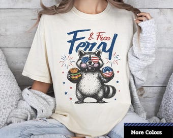 Comfort Colors® Feral And Free T-Shirt, Patriotic Raccoon Holding Burger And Donut T-shirt, 4th of July Shirt, Unisex Graphic T-Shirt.