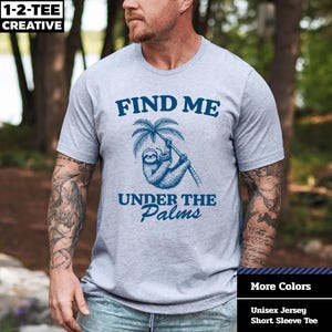 May include: A light gray unisex jersey short sleeve tee with the text "FIND ME UNDER THE PALMS" in dark blue. The graphic features a sloth hanging from a palm tree. The brand name "1-2-TEE CREATIVE" is in the top left corner.