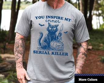 May include: A gray unisex dyed t-shirt with a blue graphic of a cat holding a knife next to a carved pumpkin. The text reads "YOU INSPIRE MY INNER SERIAL KILLER". The shirt is a Comfort Colors 1717 unisex garment.
