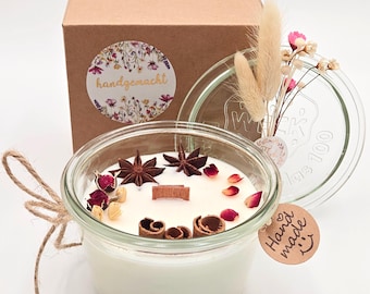 Velas festivas en un frasco de vidrio, velas perfumadas decoradas con anís estrellado real, ramas de canela y pétalos de rosa: un regalo de Navidad o una decoración de mesa.