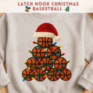 May include: A light gray sweatshirt featuring a Christmas tree made of basketballs. The tree is adorned with colorful lights and topped with a red and white Santa hat. The text "LATCH HOOK CHRISTMAS BASKETBALL" is at the top.