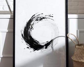 May include: Black and white abstract art print in a black frame. The artwork features a dynamic brushstroke design forming a circular shape. A woven basket with handles sits on the floor. A model ship and a tripod are in the background.