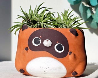 Terrakottakruka av tanuki. Handgjord lerkruka med djurmotiv och dränering.