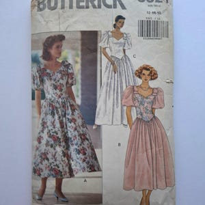 May include: A vintage sewing pattern for a dress, featuring three different styles. The pattern is from Butterick and is size 12-14. The dress styles include a floral print, a white dress with puff sleeves, and a pink dress with puff sleeves.