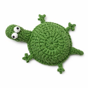 May include: A handmade green crochet turtle toy with white and black eyes. The turtle has a round body, a long neck, and four small legs. The toy is made of a soft, textured yarn and is likely a children's toy.