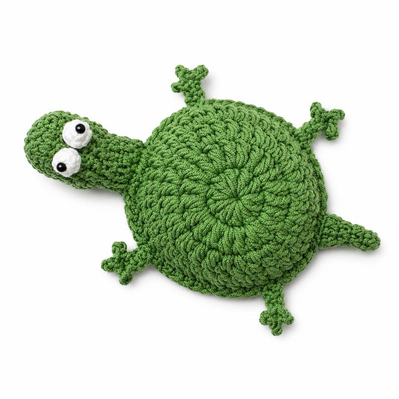 May include: A handmade green crochet turtle toy with white and black eyes. The turtle has a round body, a long neck, and four small legs. The toy is made of a soft, textured yarn and is likely a children's toy.