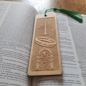 May include: A wooden bookmark with a green tassel. The bookmark features a laser-engraved design of the One Ring, the White Tree of Gondor, and the entrance to the Mines of Moria from The Lord of the Rings.