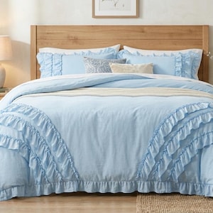 Pode incluir: Um conjunto de roupa de cama azul-claro com uma capa de edredão com folhos em cascata nas laterais e fronhas a condizer. O conjunto inclui um edredão azul-claro liso, duas fronhas com folhos e duas almofadas decorativas mais pequenas.