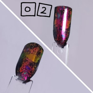 Puede incluir: Dos muestras de esmalte de u&ntilde;as en palitos de pl&aacute;stico transparente etiquetados con el n&uacute;mero 02. Las muestras presentan una base negra cubierta con escamas iridiscentes multicolores que cambian entre tonos de rosa, naranja, verde y morado.