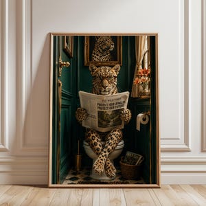 Könnte beinhalten: Ein gerahmter Kunstdruck, der einen Leoparden mit Brille zeigt, der in einem dunkelgrünen Raum auf einer Toilette sitzt. Der Leopard hält eine Zeitung mit dem Titel The Wild Times und dem Text Protect Our Jungles Protect Our Future. Darüber hängt ein Leopardenporträt.