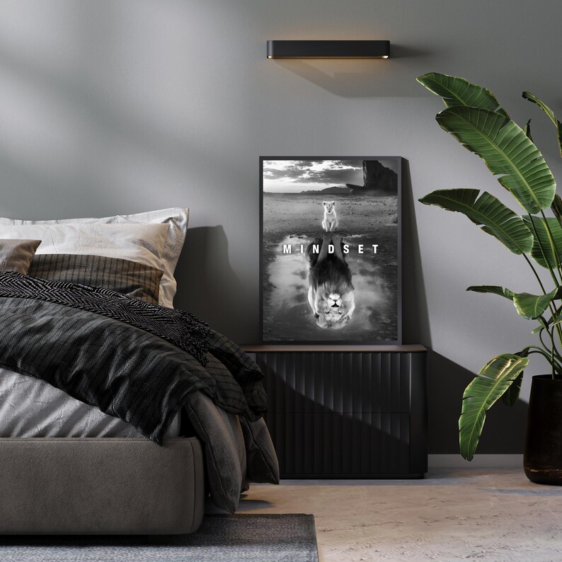 May include: Black and white framed print with the word "MINDSET" and a lion image. The artwork is displayed above a black nightstand in a bedroom setting. A large green plant is in a black pot to the right of the nightstand.