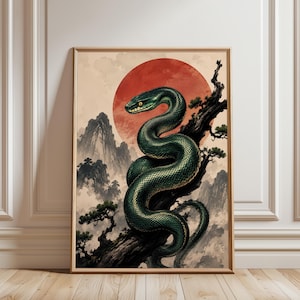 Puede incluir: Una lámina de arte enmarcada que muestra una serpiente de color verde oscuro enroscada en la rama nudosa de un árbol. El fondo presenta un gran sol rojo, montañas brumosas y pequeños pinos en un estilo artístico con tonos beige.