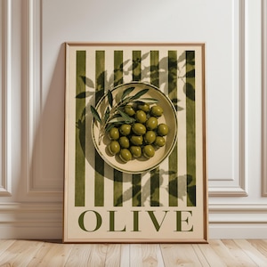 May include: A framed wall art print featuring a bowl of green olives topped with an olive branch. The background consists of vertical olive green and cream stripes. The word OLIVE is printed in large, bold, dark green capital letters at the bottom.