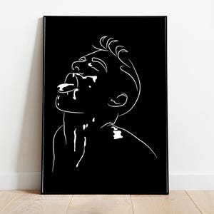May include: A framed black and white line drawing. The artwork depicts a person looking upwards with their mouth open and tongue extended. The minimalist design uses white lines on a black background, in a black frame.