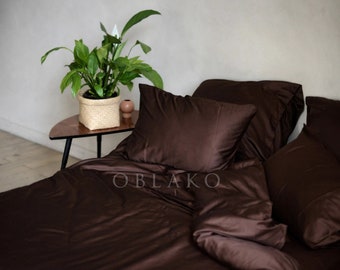 May include: A brown satin duvet cover and pillowcases with the word "OBLAKO" printed on the duvet cover.