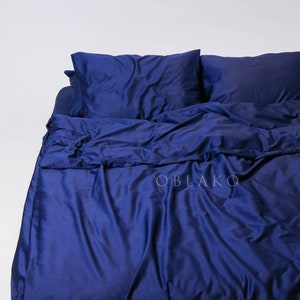 May include: A deep blue duvet cover and two matching pillowcases. The duvet cover is made of a soft, silky fabric and has a smooth, wrinkle-free finish.