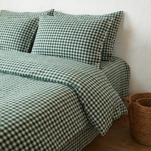 以下が含まれることがあります： 緑と白のギンガムチェック柄のベッドセット。木製のボタンが付いた枕カバー2枚、掛け布団カバー、ベッドスカートが含まれています。コーナーには織りのバスケットがあります。